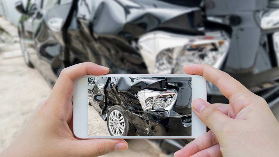 Unfallwagenankauf Miltenberg: Unfallschaden an einem Auto wird mit dem Smartphone fotografiert.
